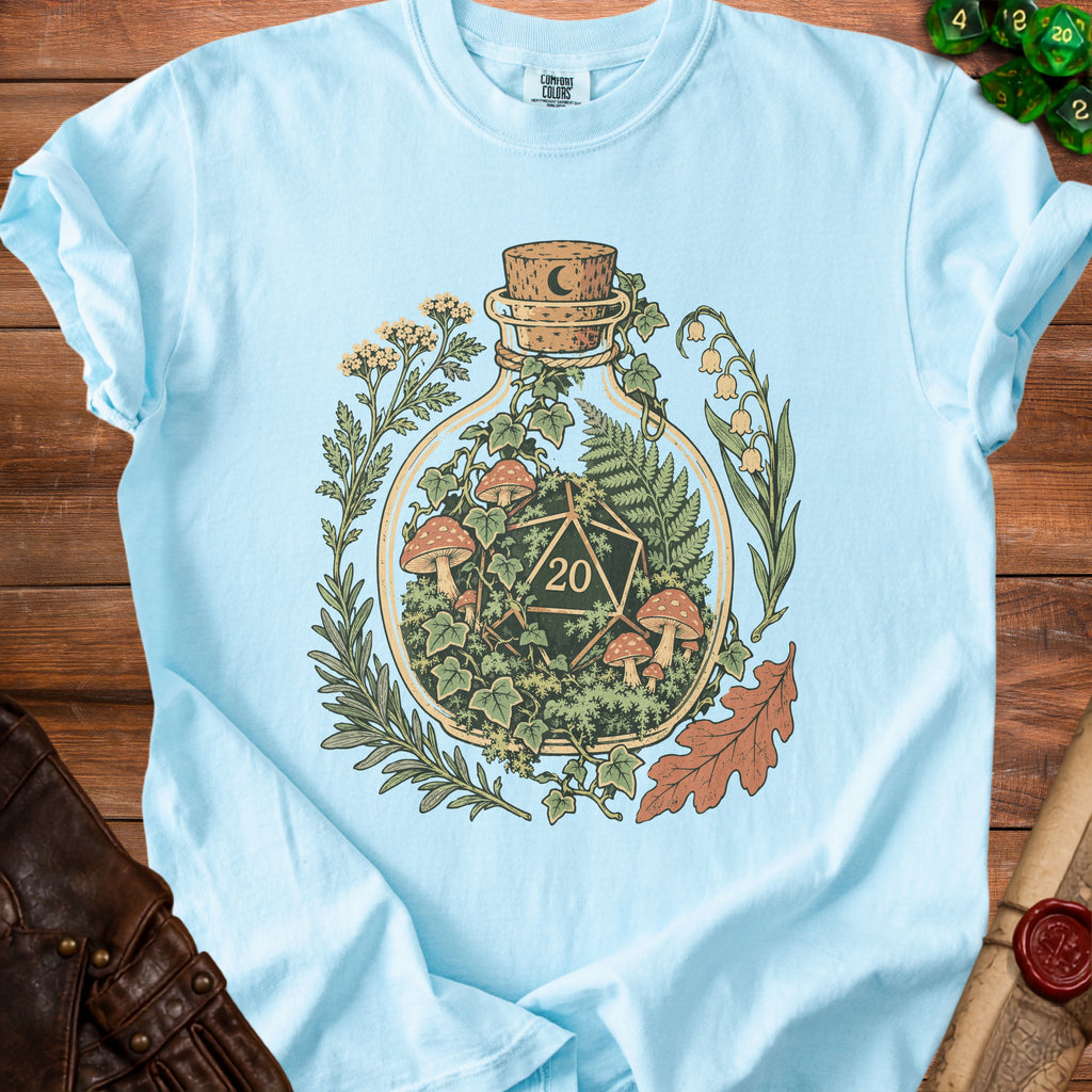 Light blue t-shirt with a glass bottle graphic containing a d20 die and mushrooms.