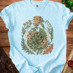 Light blue t-shirt with a glass bottle graphic containing a d20 die and mushrooms.