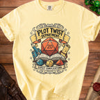 Pale yellow t-shirt with "Plot Twist Department Expect Complications" graphic and dice.