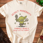 Cream t-shirt with "Reject Modernity Embrace Being a Silly Little Goblin" text and goblin graphic.