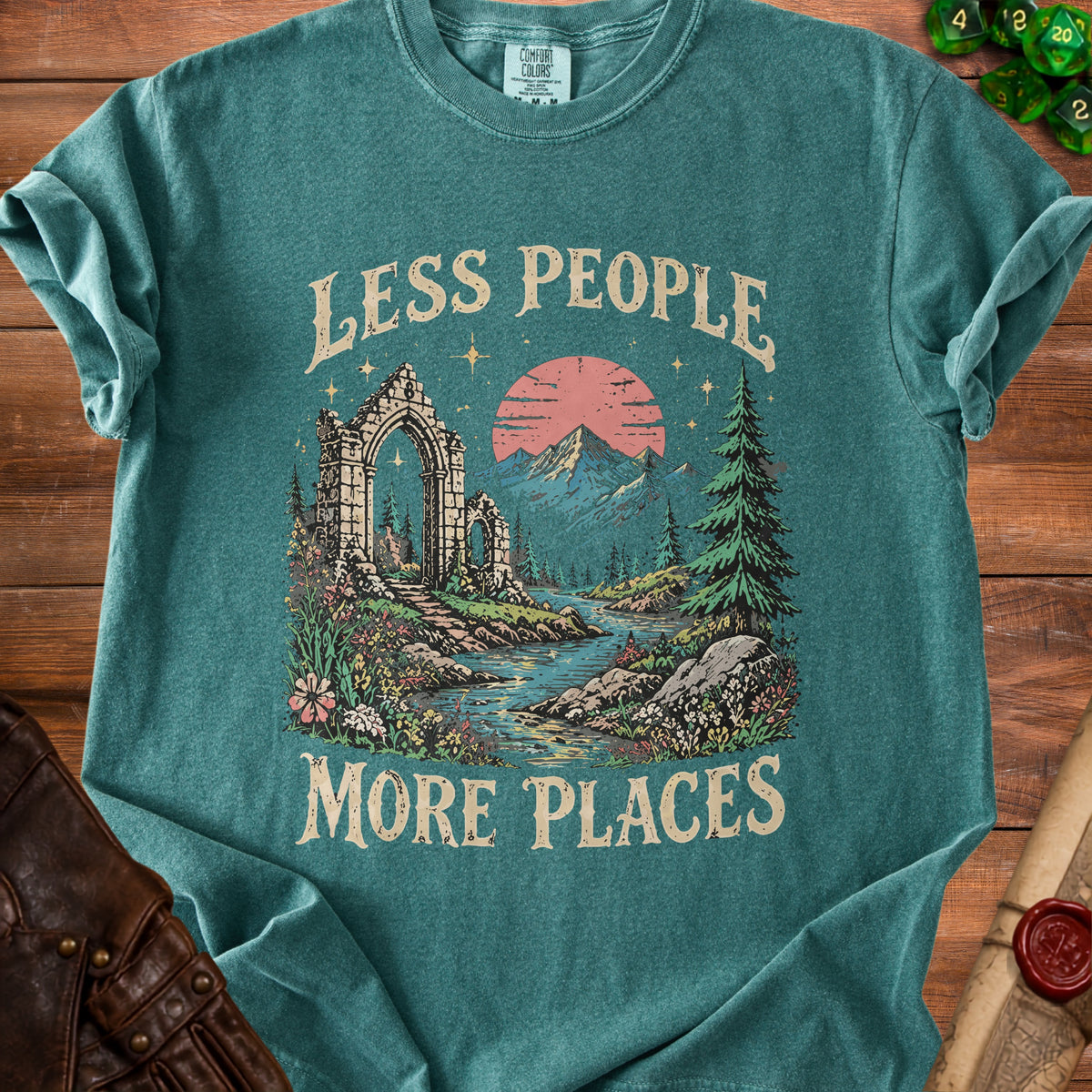 Teal t-shirt with "Less People More Places" text and scenic ruins and mountains graphic.