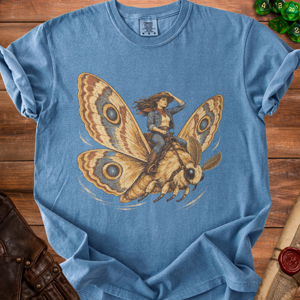 Blue t-shirt with graphic of cowgirl riding a moth with large wings.