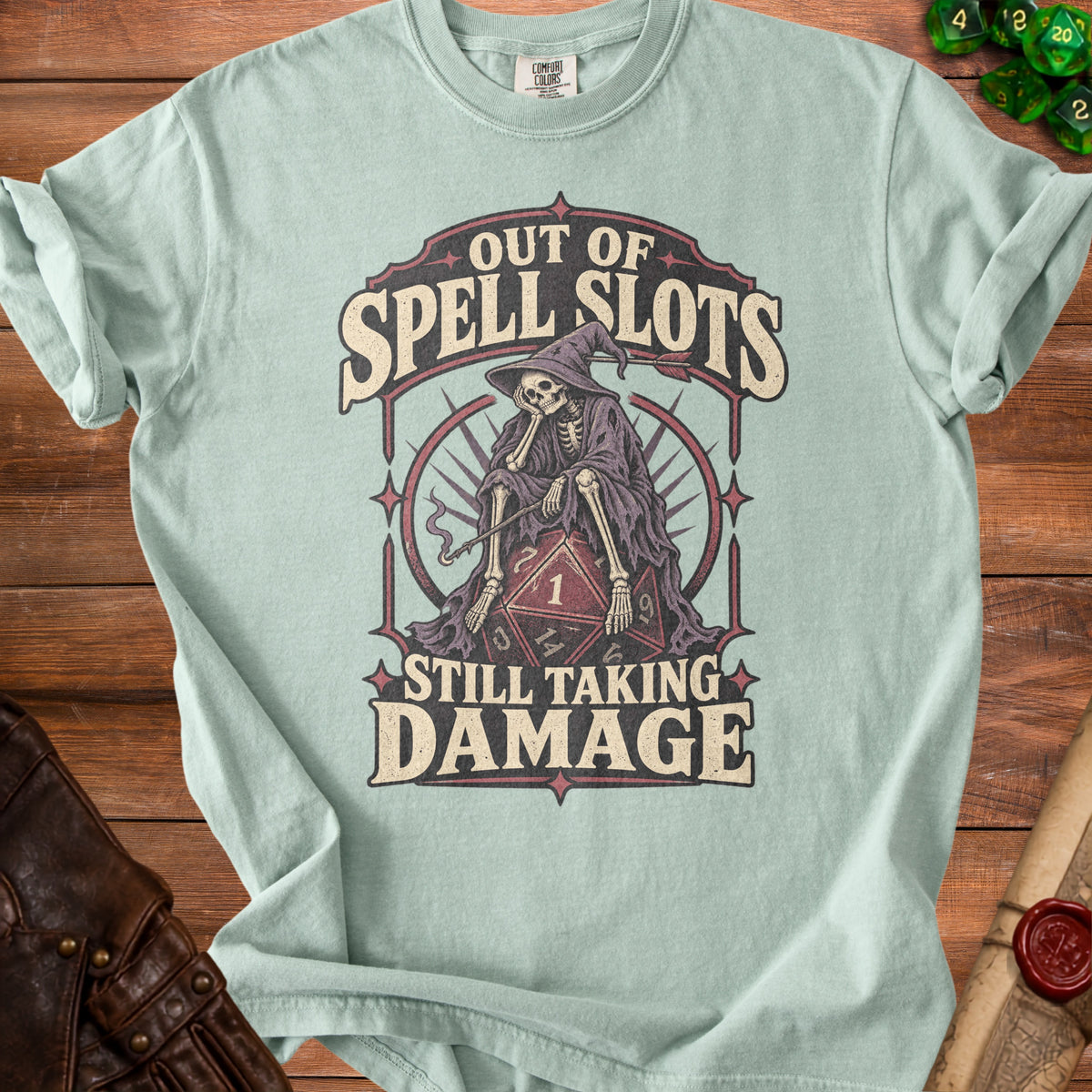 T-shirt with skeleton wizard on dice, reads "Out of Spell Slots Still Taking Damage".