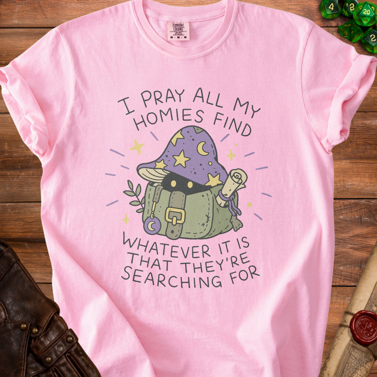 Pink t-shirt with a mushroom graphic and text "I PRAY ALL MY HOMIES FIND WHATEVER IT IS THAT THEY'RE SEARCHING FOR".