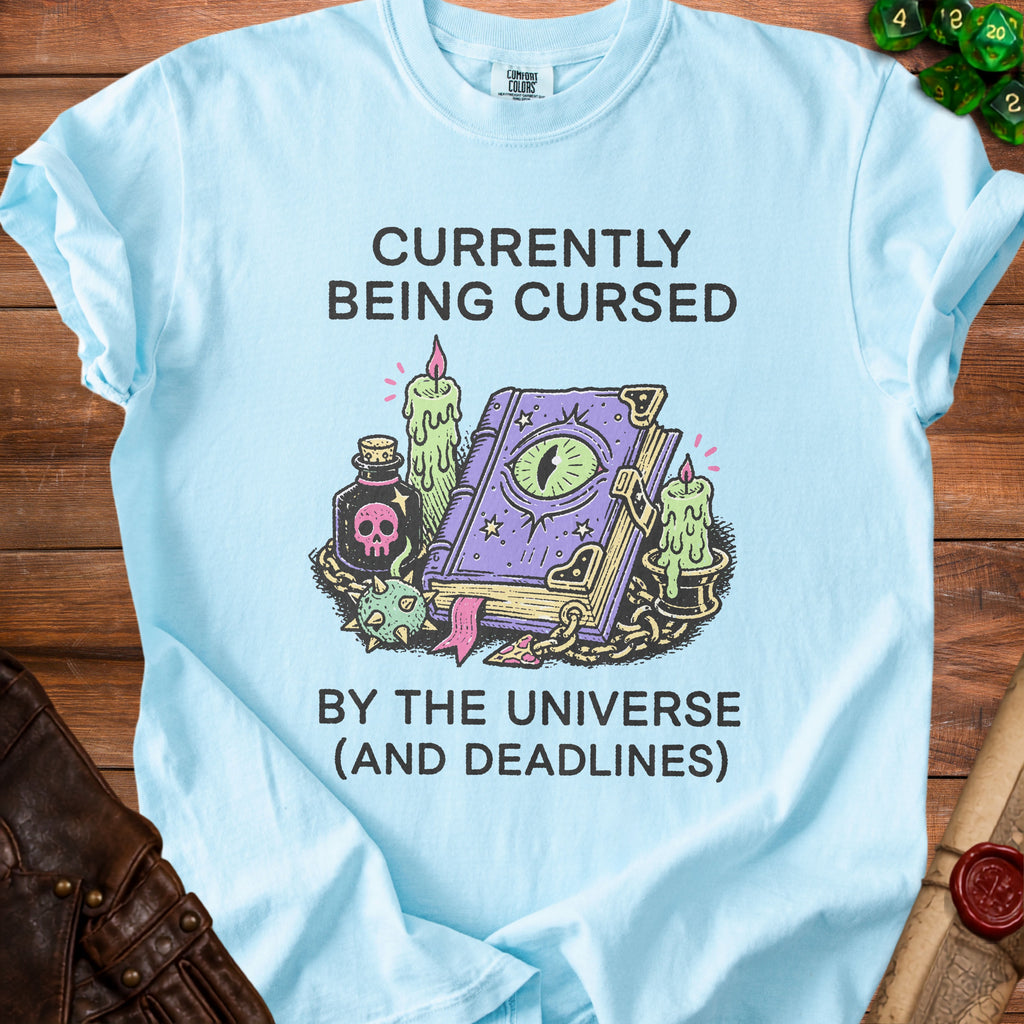 Light blue t-shirt with "Currently Being Cursed by the Universe (And Deadlines)" text.