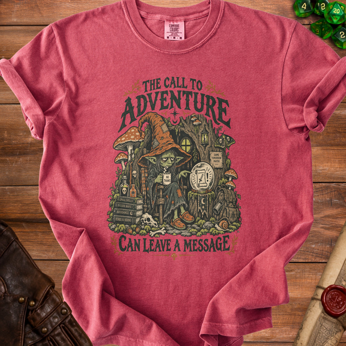 T-shirt graphic with a witch and mushrooms, text "The Call to Adventure Can Leave a Message".