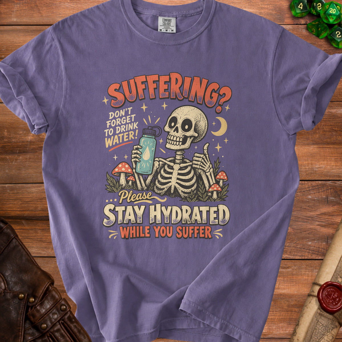 Purple t-shirt with skeleton graphic and text "Suffering? Don't forget to drink water! Please stay hydrated while you suffer."