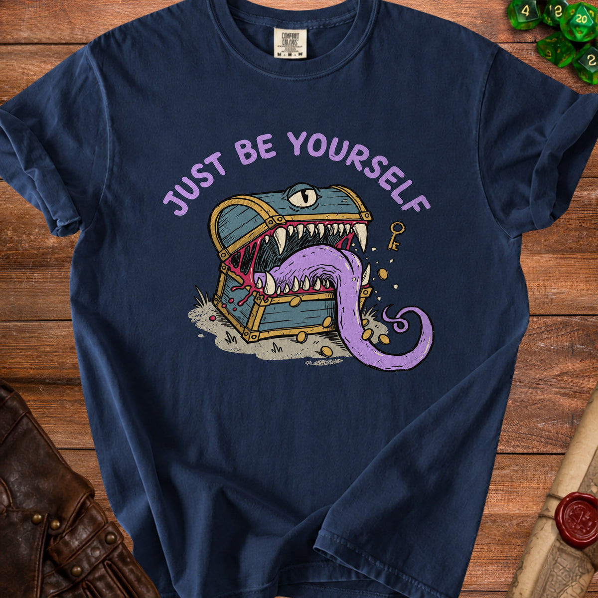 Navy t-shirt with a treasure chest monster graphic and "JUST BE YOURSELF" text.