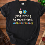 Black t-shirt with "just trying to make friends with necromancy" text and icons.