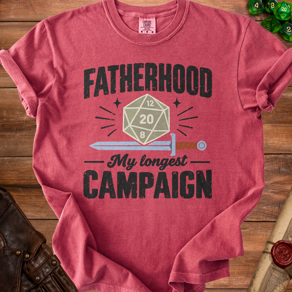 Red t-shirt with "FATHERHOOD My longest CAMPAIGN" text, D20 die, and sword graphic.