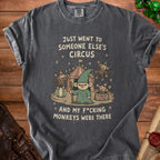 Dark grey t-shirt graphic: gnome and monkeys at a circus with text.