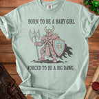 Light blue t-shirt with a knight graphic and text "BORN TO BE A BABY GIRL FORCED TO BE A BIG DAWG."