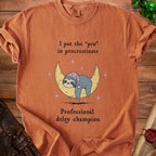 Orange t-shirt with text "I put the 'pro' in procrastinate" and a sleeping sloth on a moon.