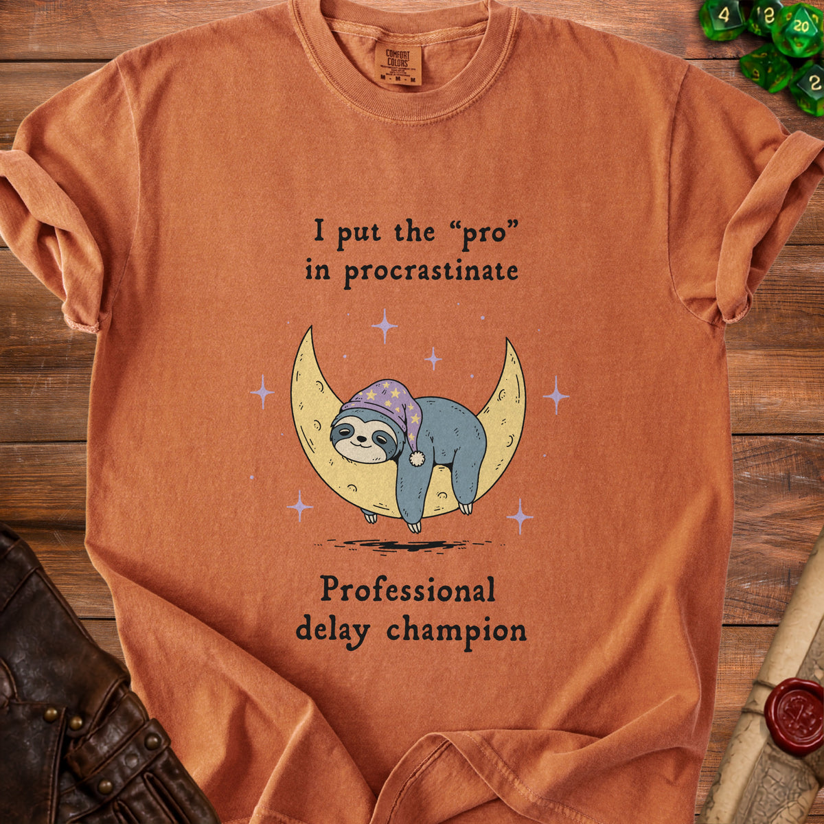 Orange t-shirt with text "I put the 'pro' in procrastinate" and a sleeping sloth on a moon.