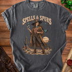 Graphic tee with "Spells & Spurs" text, a witchy cowgirl, and desert landscape.
