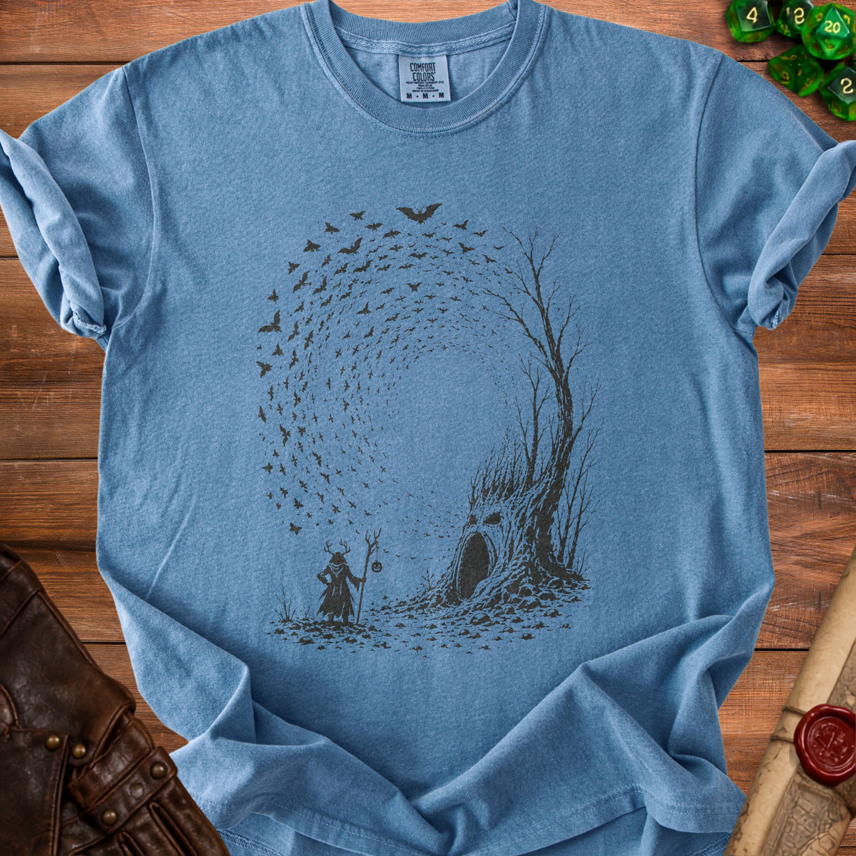 Blue t-shirt with woodland scene: figure with antlers, bats, and a face in a tree.