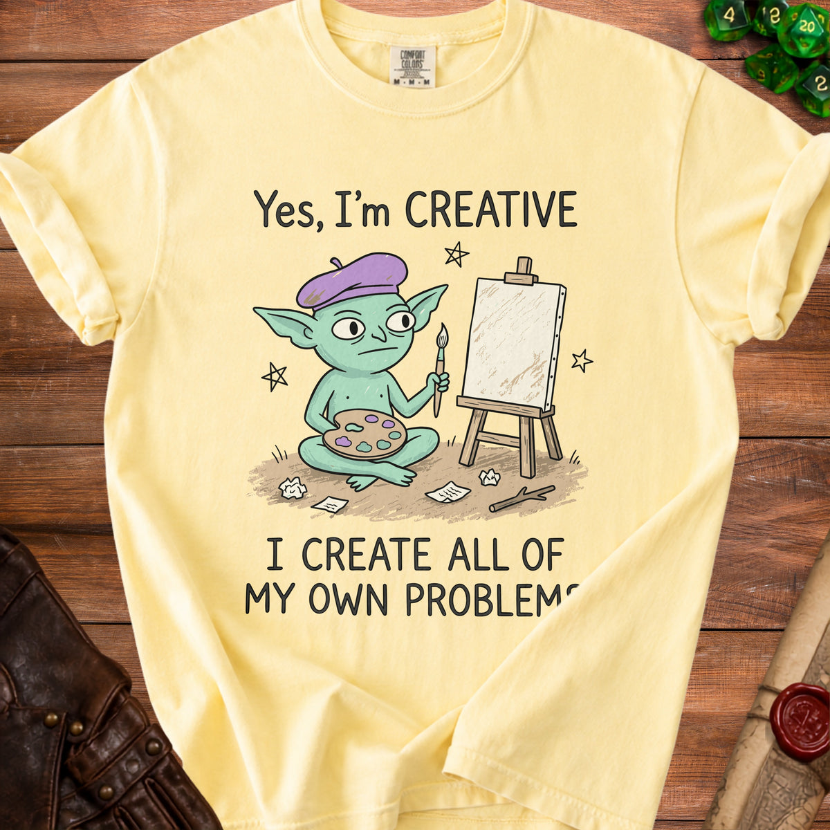 Yellow t-shirt with cartoon creature, easel, and text: "Yes, I'm CREATIVE I CREATE ALL OF MY OWN PROBLEMS".