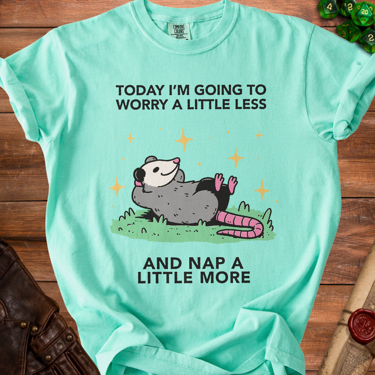 Aquamarine t-shirt with a drawing of a possum and the text "Today I'm going to worry a little less and nap a little more".