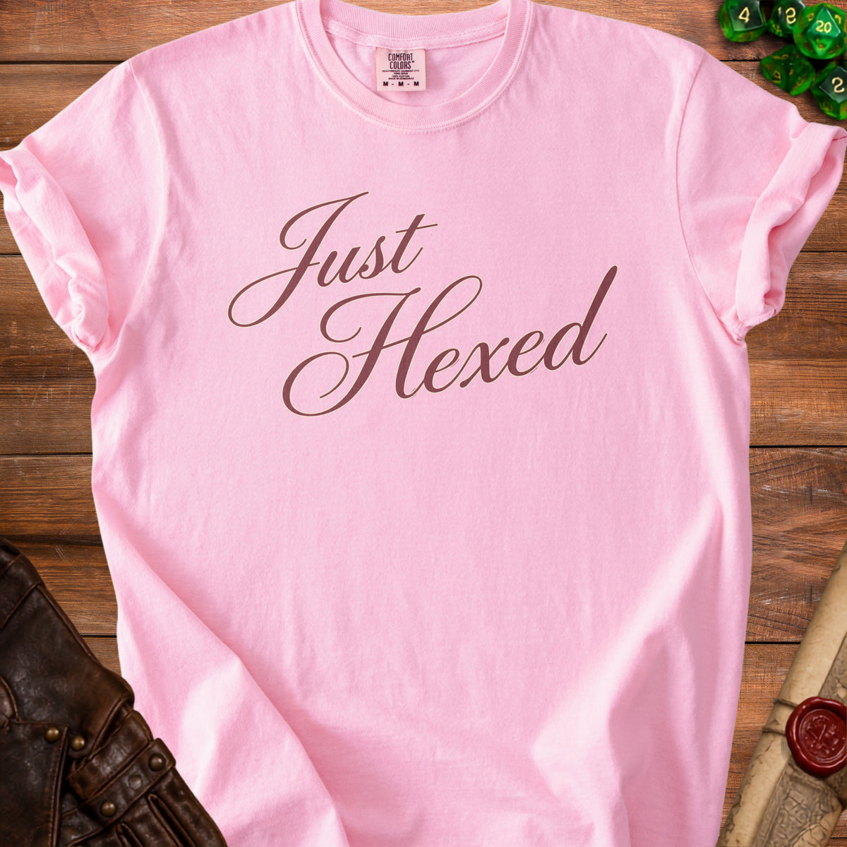 Pink t-shirt with "Just Hexed" text in cursive brown font.