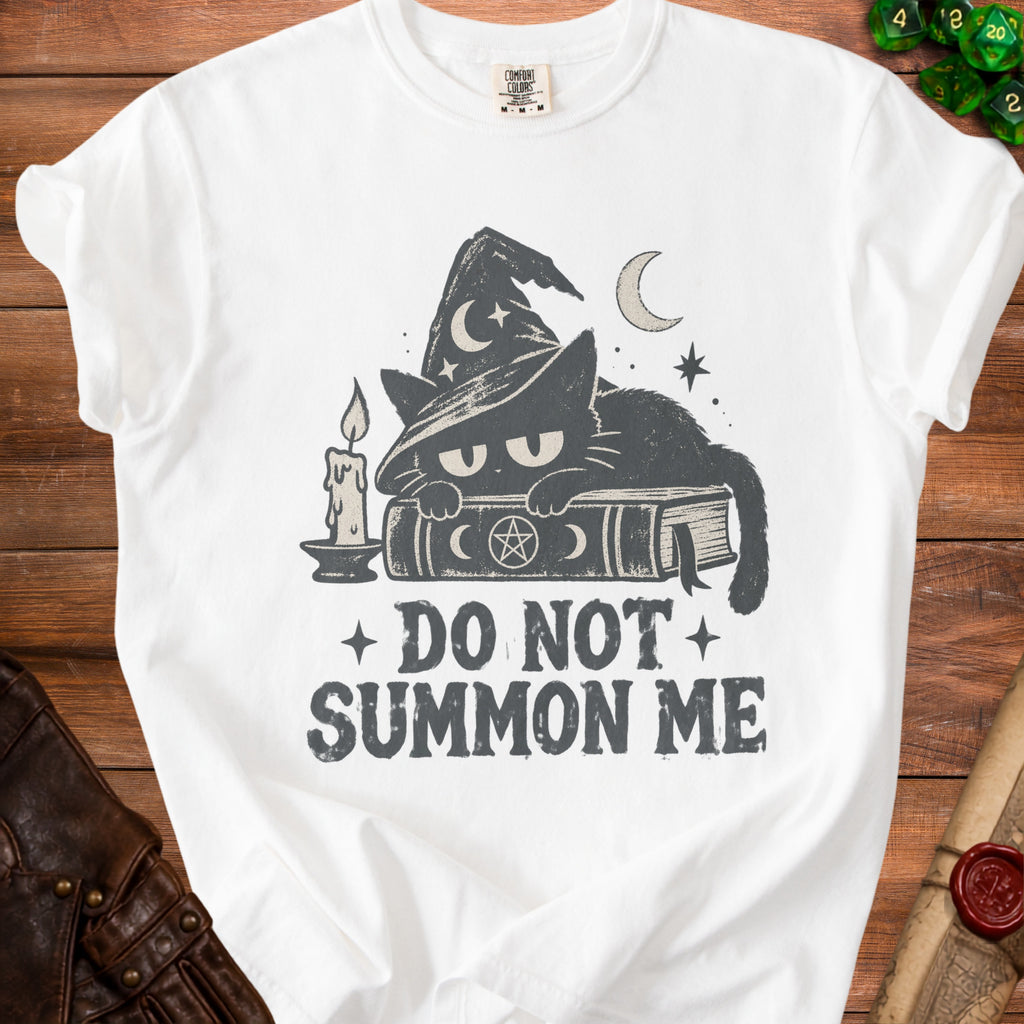 White t-shirt with black cat in witch hat, book, candle, text "DO NOT SUMMON ME".