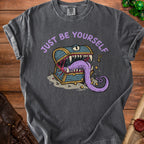 Dark gray t-shirt with purple text "JUST BE YOURSELF" and a monster chest graphic.