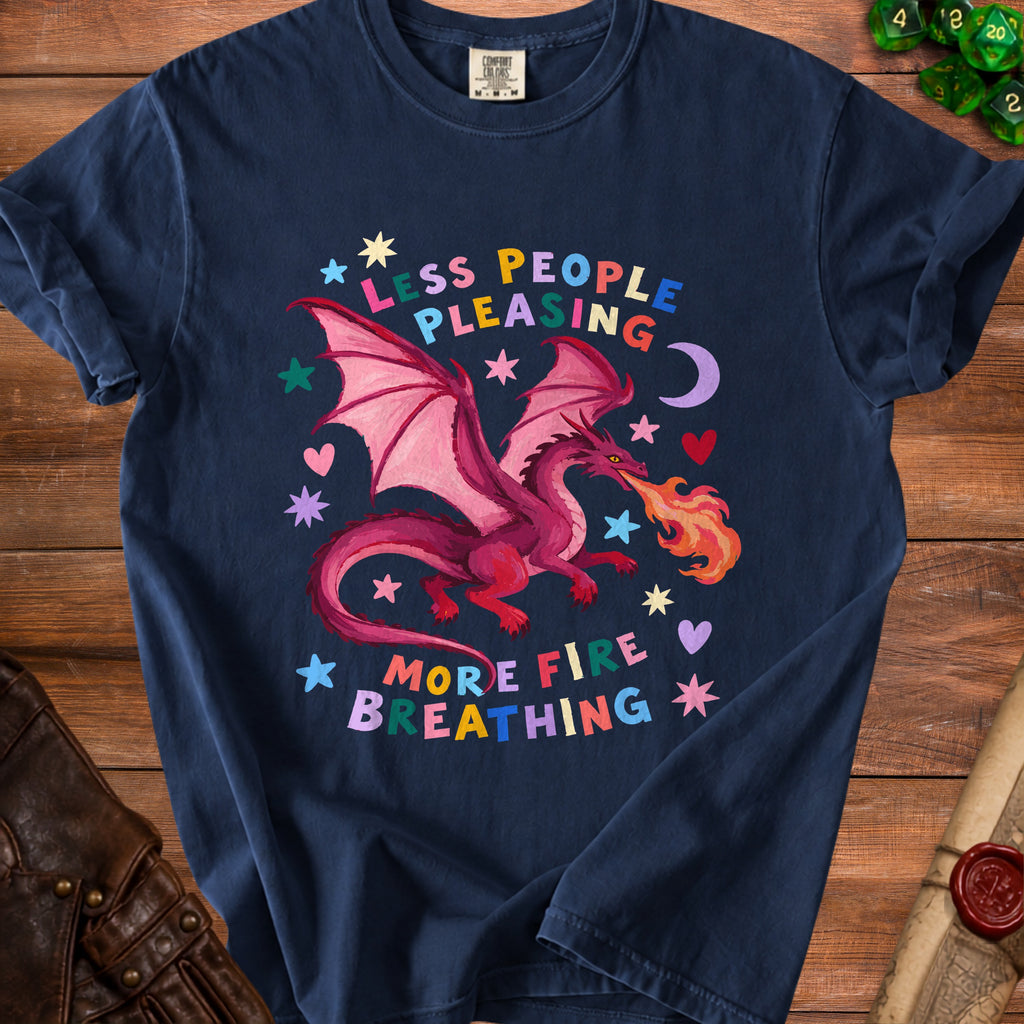Dark blue t-shirt with a pink dragon breathing fire and text "Less People Pleasing More Fire Breathing".
