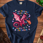 Dark blue t-shirt with a pink dragon breathing fire and text "Less People Pleasing More Fire Breathing".
