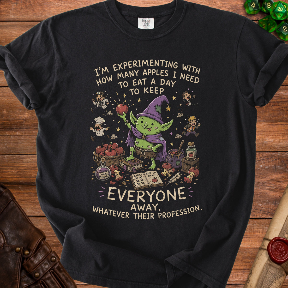 T-shirt with a goblin holding an apple and the text "I'm experimenting with how many apples I need to eat a day to keep everyone away."