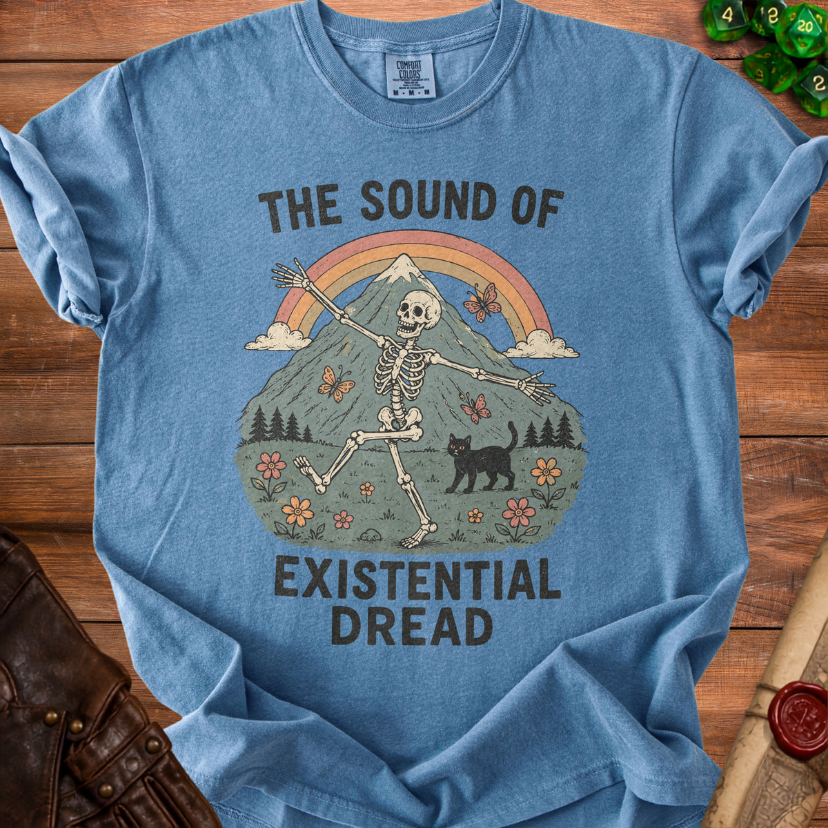 Blue t-shirt with skeleton, cat, mountain, rainbow, and text "The Sound of Existential Dread".