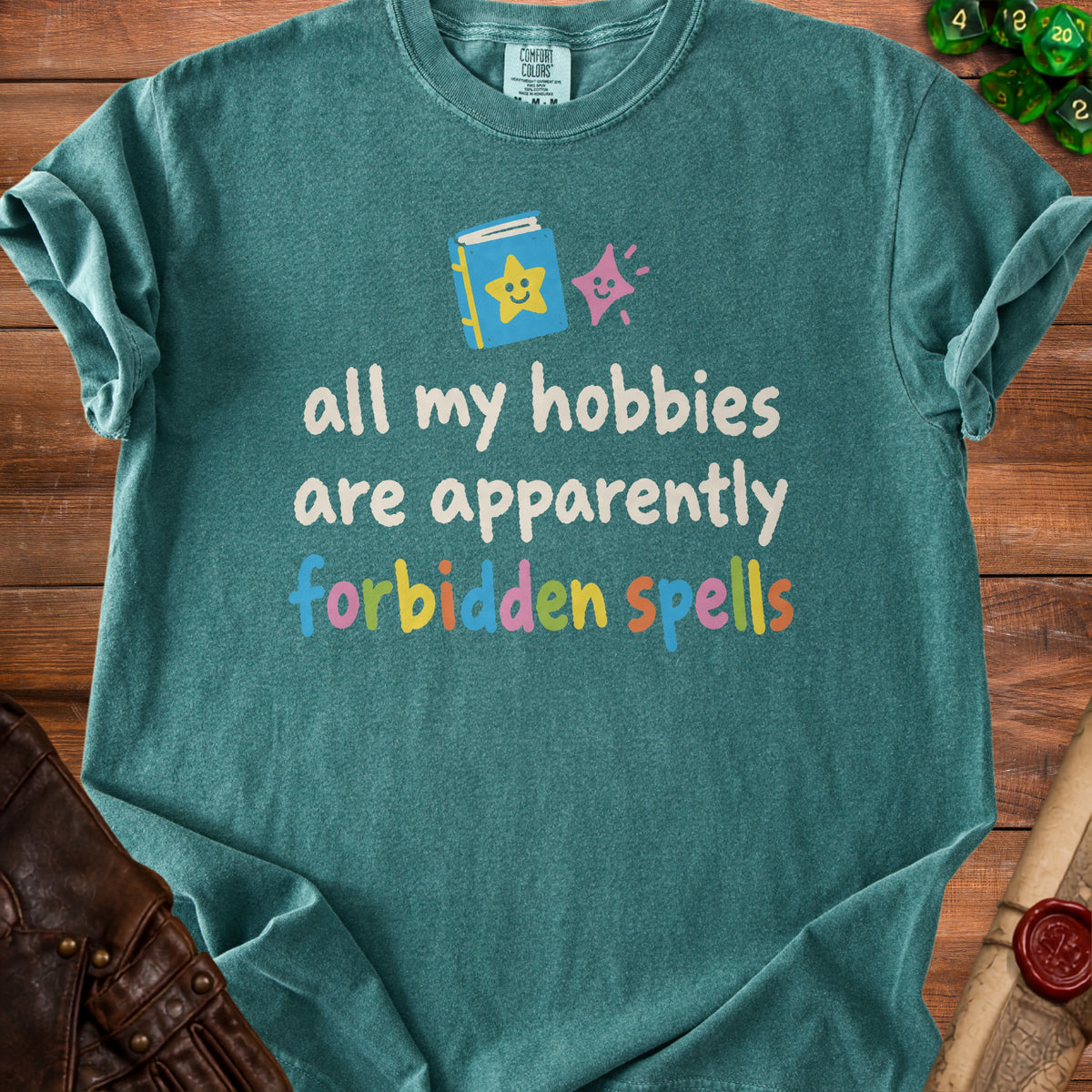 Green t-shirt with text "all my hobbies are apparently forbidden spells".