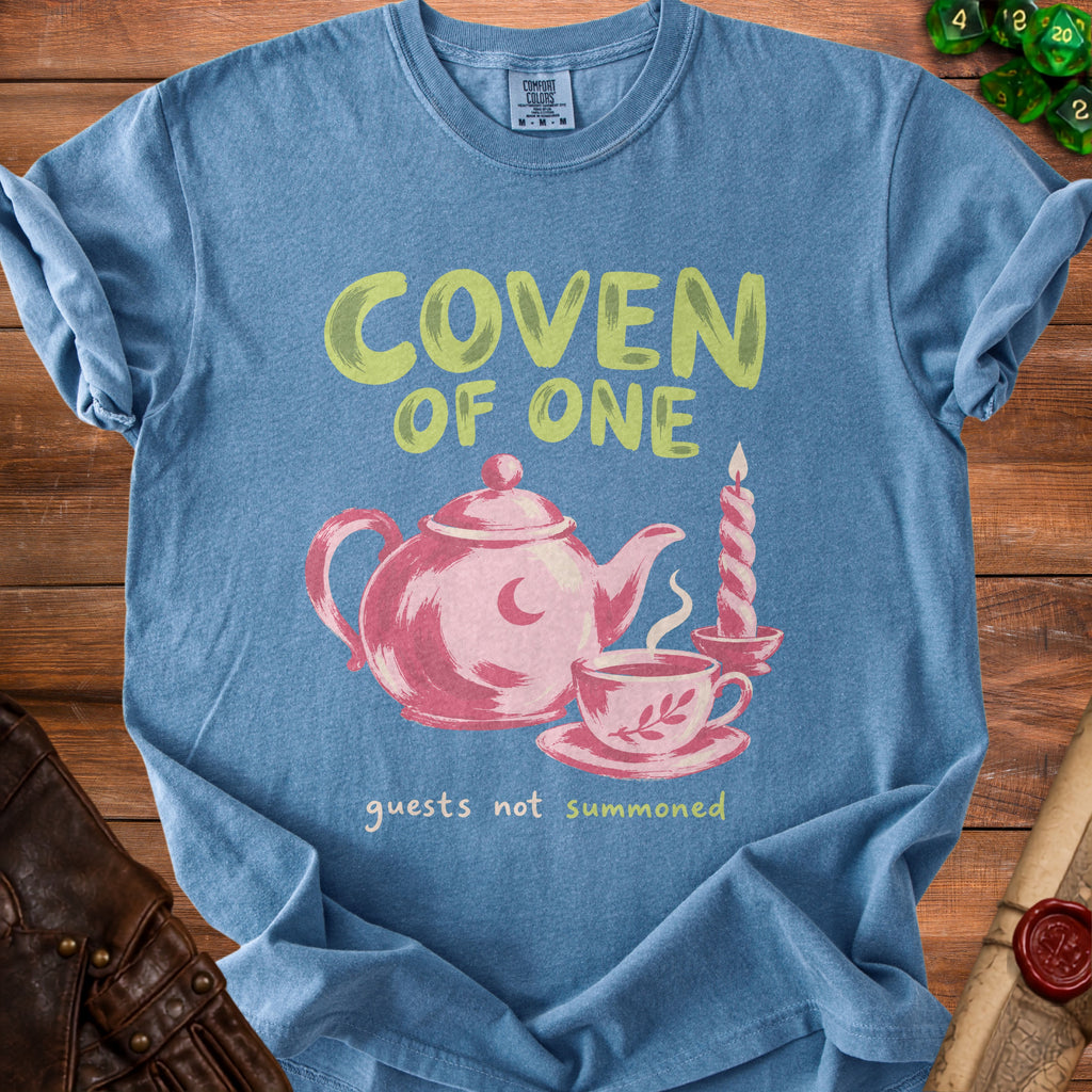Blue t-shirt with "Coven of One" and a teapot, cup, and candle.