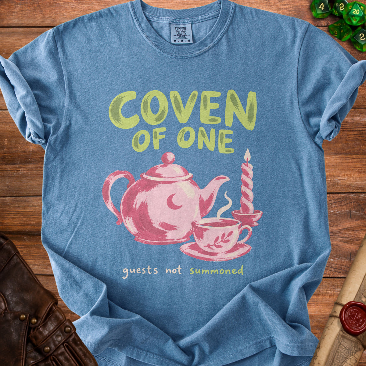Blue t-shirt with "Coven of One" and a teapot, cup, and candle.