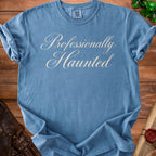 Blue t-shirt with "Professionally Haunted" in cursive text.