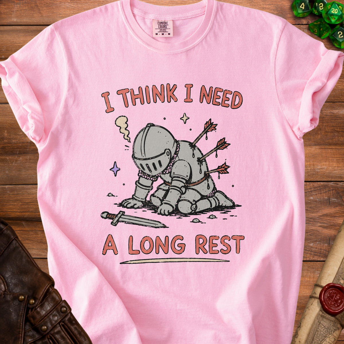 Pink t-shirt with a knight impaled by arrows and text "I THINK I NEED A LONG REST".