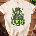 Cream t-shirt with a green grim reaper graphic and "RESTING LICH FACE" text.