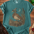 Mallard duck wearing a wizard hat and cloak by reeds and mushrooms.