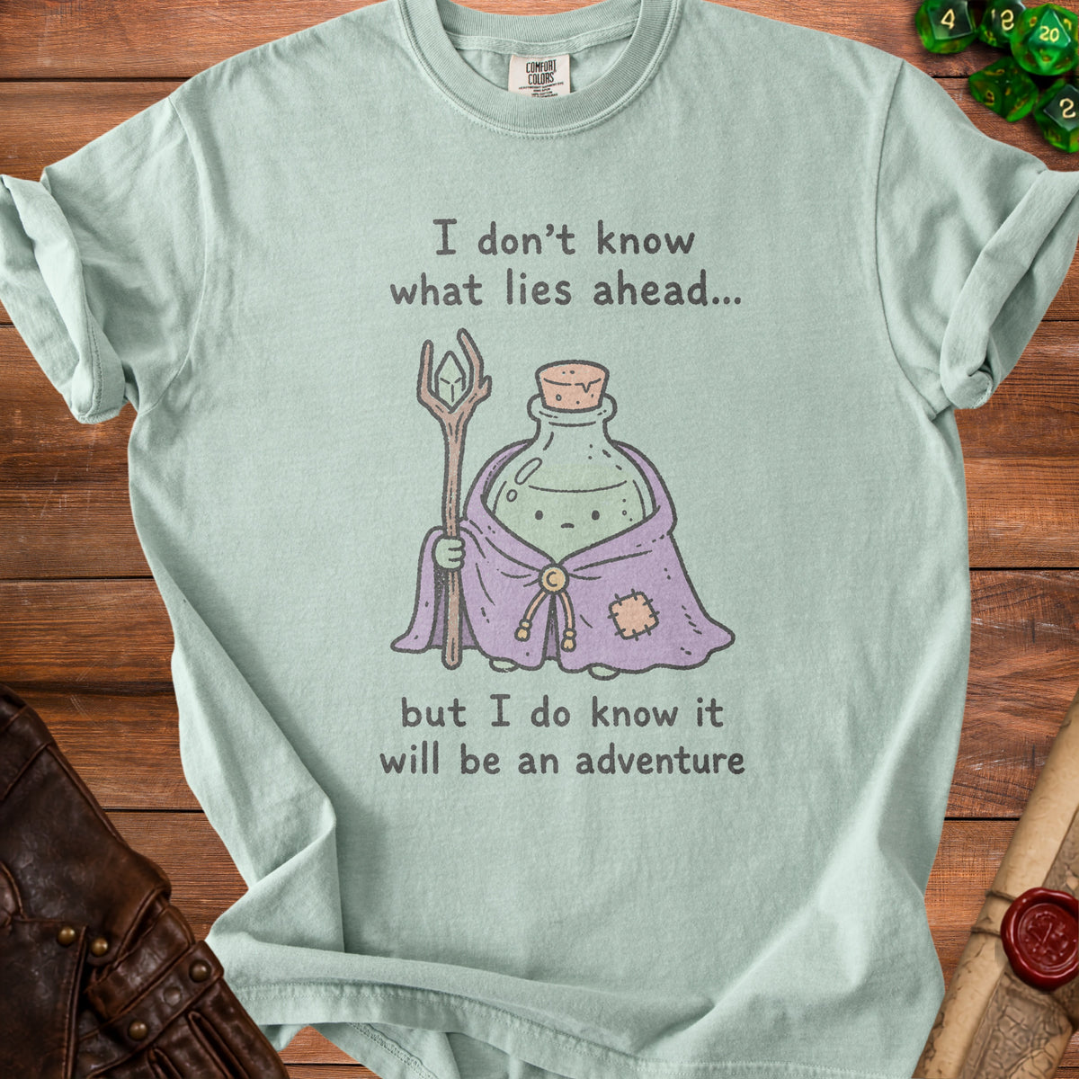 Pale green t-shirt with a potion character holding a staff and the text "I don't know what lies ahead... but I do know it will be an adventure".