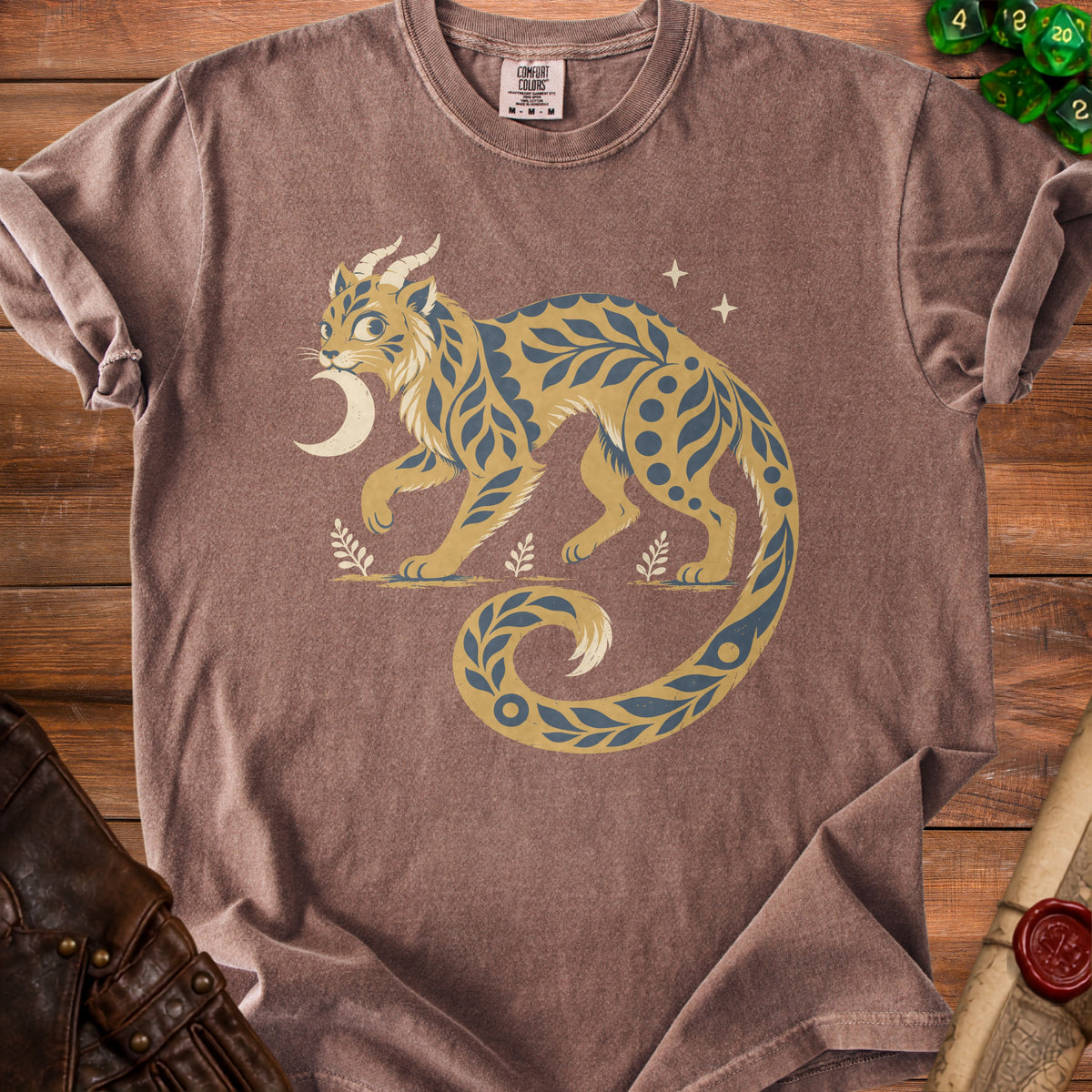 Brown t-shirt with a stylized tan and blue feline creature and moon graphic.