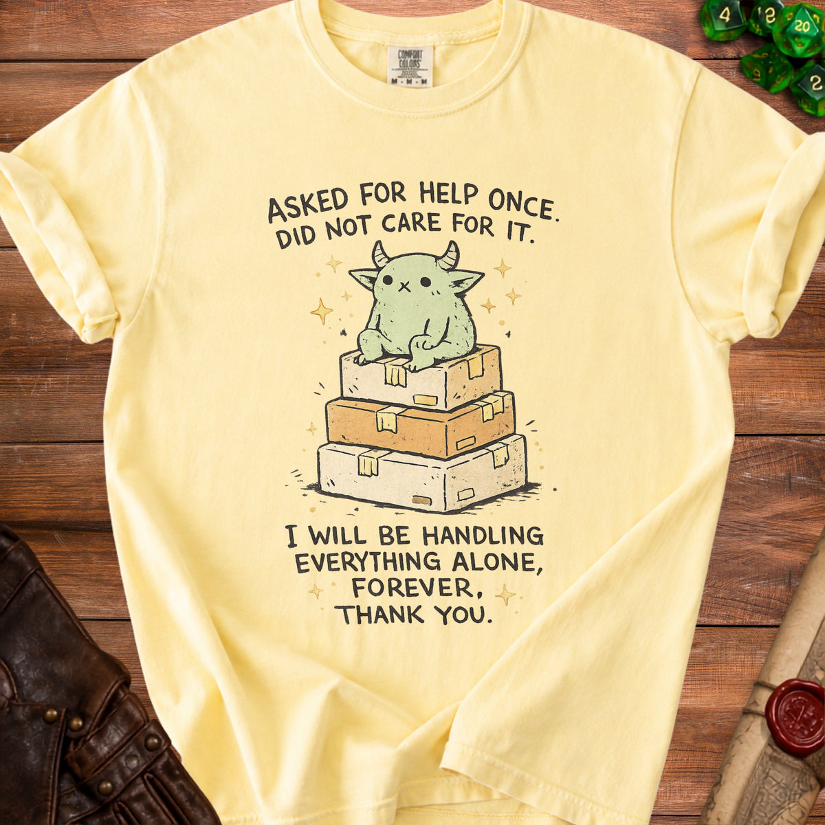 Yellow t-shirt with a cartoon creature sitting on stacked boxes and text.