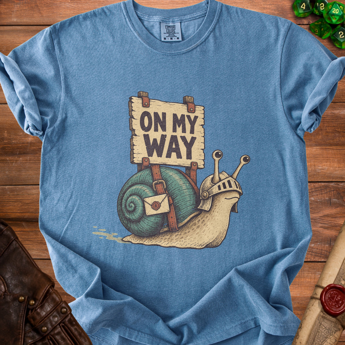 T-shirt graphic of a snail knight with a sign reading "ON MY WAY."