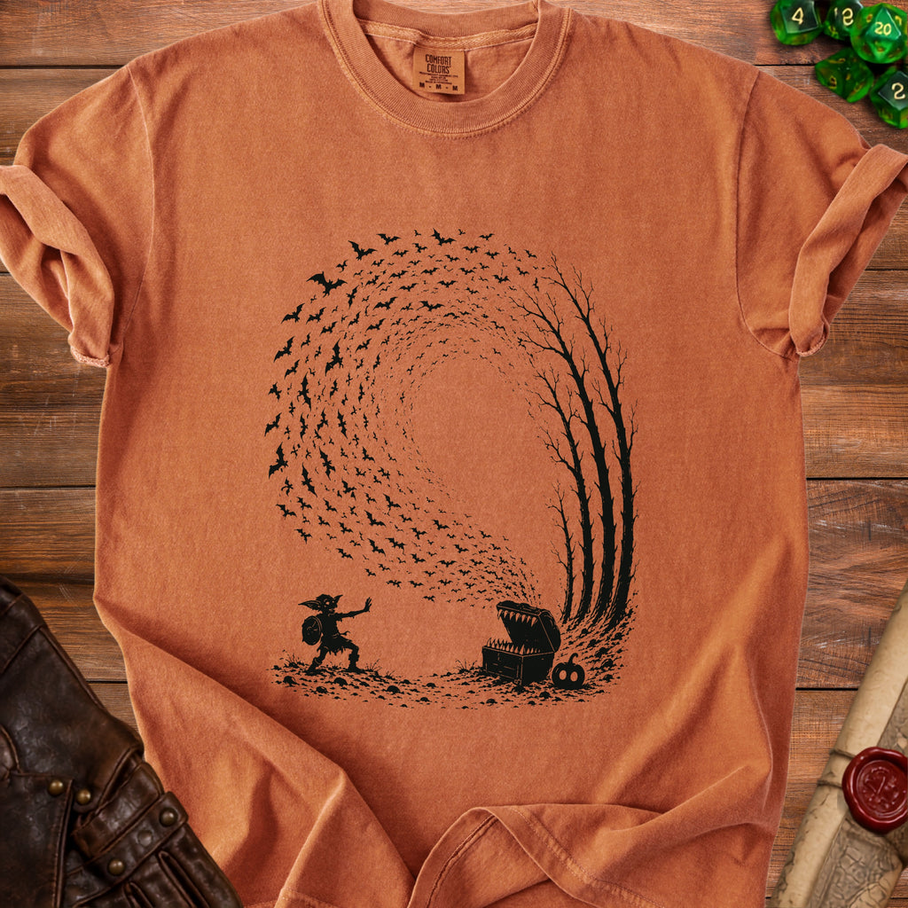Goblin facing open treasure chest with bats flying out, on a burnt orange t-shirt.
