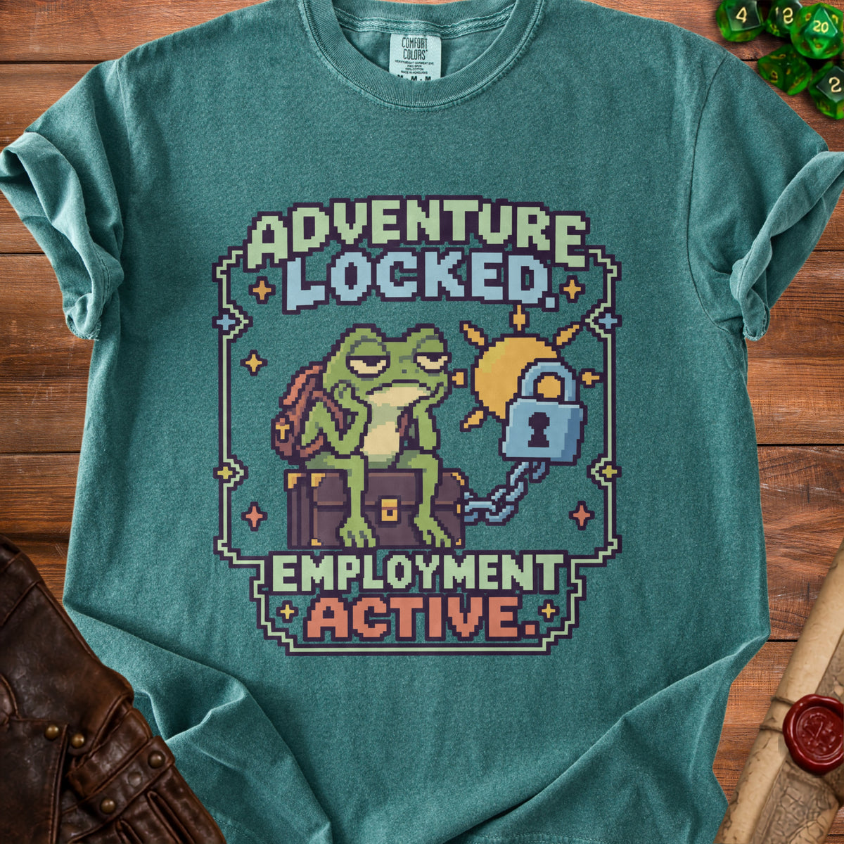 A green t-shirt with pixel art of a bored frog sitting on a locked chest, with text reading Adventure Locked, Employment Active.