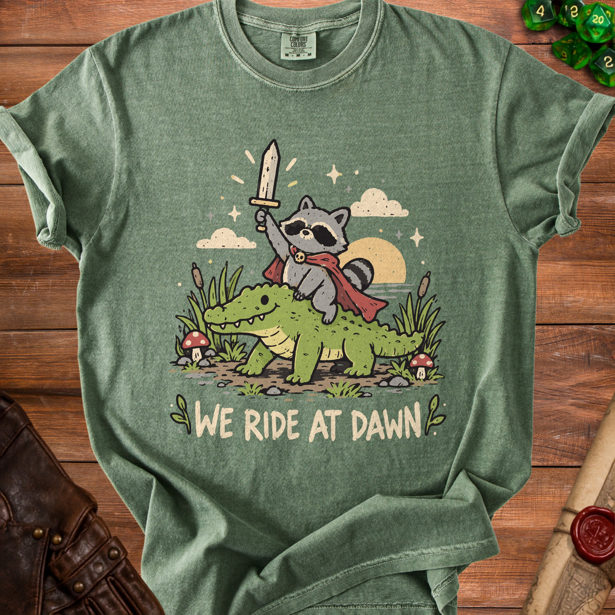 Cartoon raccoon in cape riding an alligator, with text "We Ride at Dawn".
