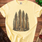 Yellow t-shirt with graphic of whimsical forest creatures and sequoia trees.