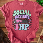 T-shirt with text "SOCIAL BATTERY: 1HP", pixel heart, and battery graphic.
