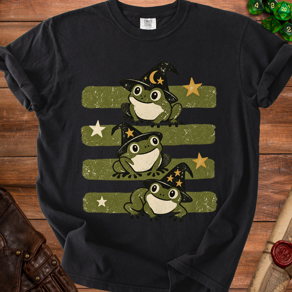 Black t-shirt with three cartoon frogs wearing witch hats and stars.