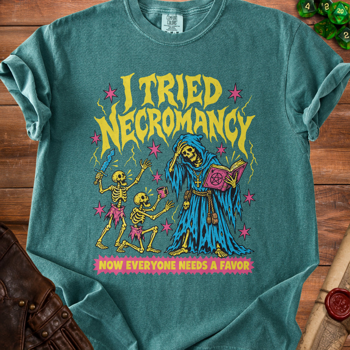 T-shirt graphic of skeletons and a hooded figure with text "I TRIED NECROMANCY NOW EVERYONE NEEDS A FAVOR".