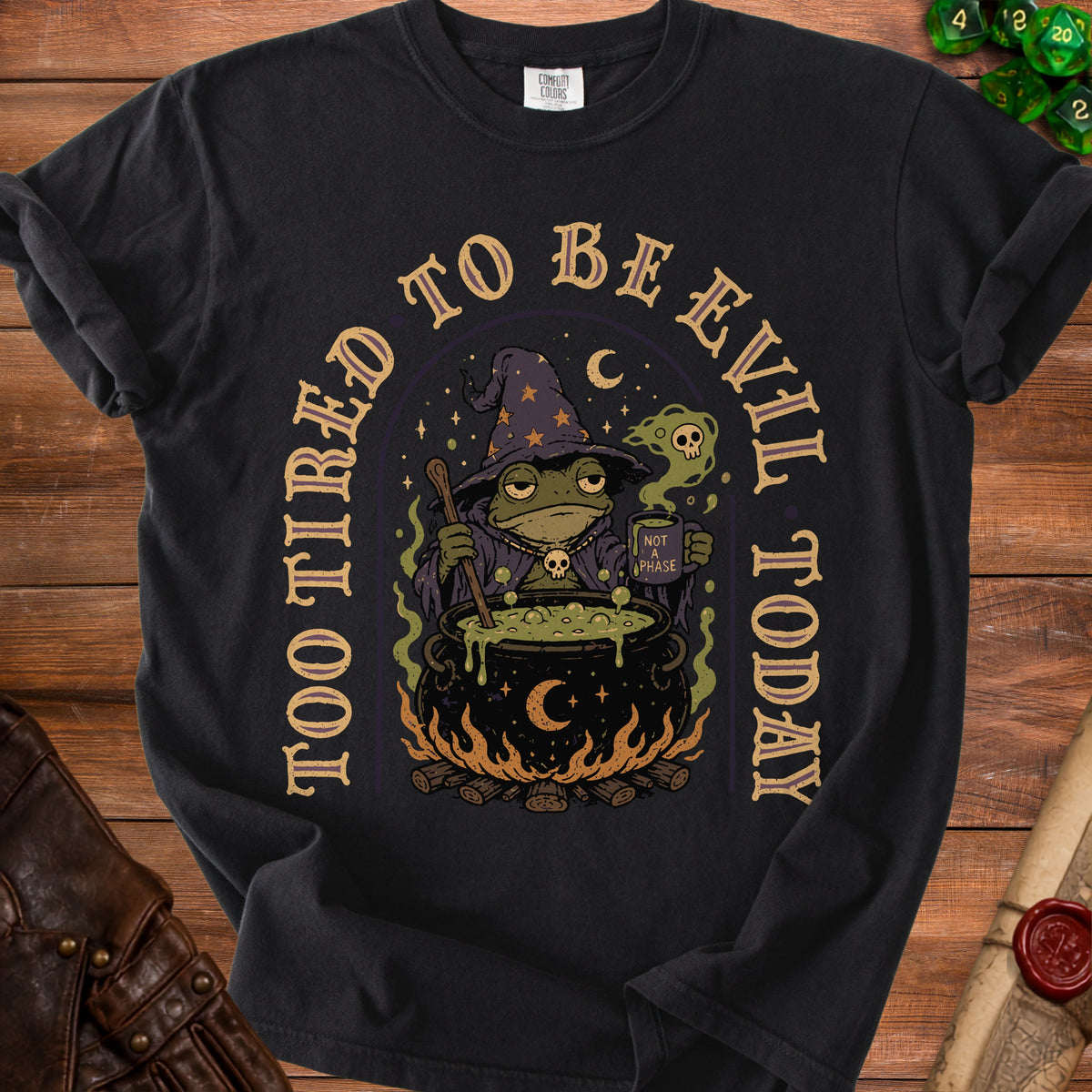 Black t-shirt with a wizard frog stirring a cauldron; "Too Tired to Be Evil Today" text.