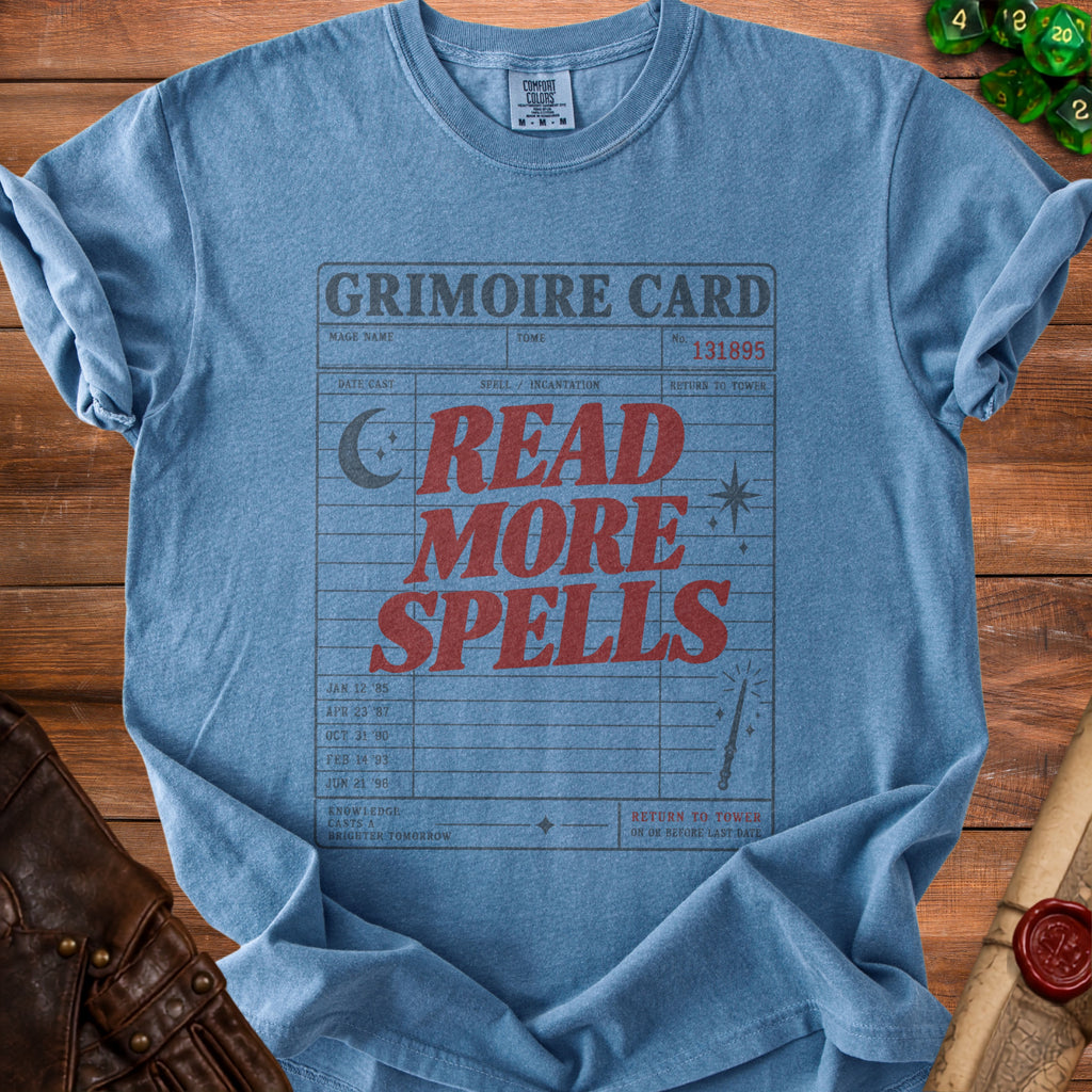 Blue t-shirt with "Grimoire Card Read More Spells" text and magical graphics.