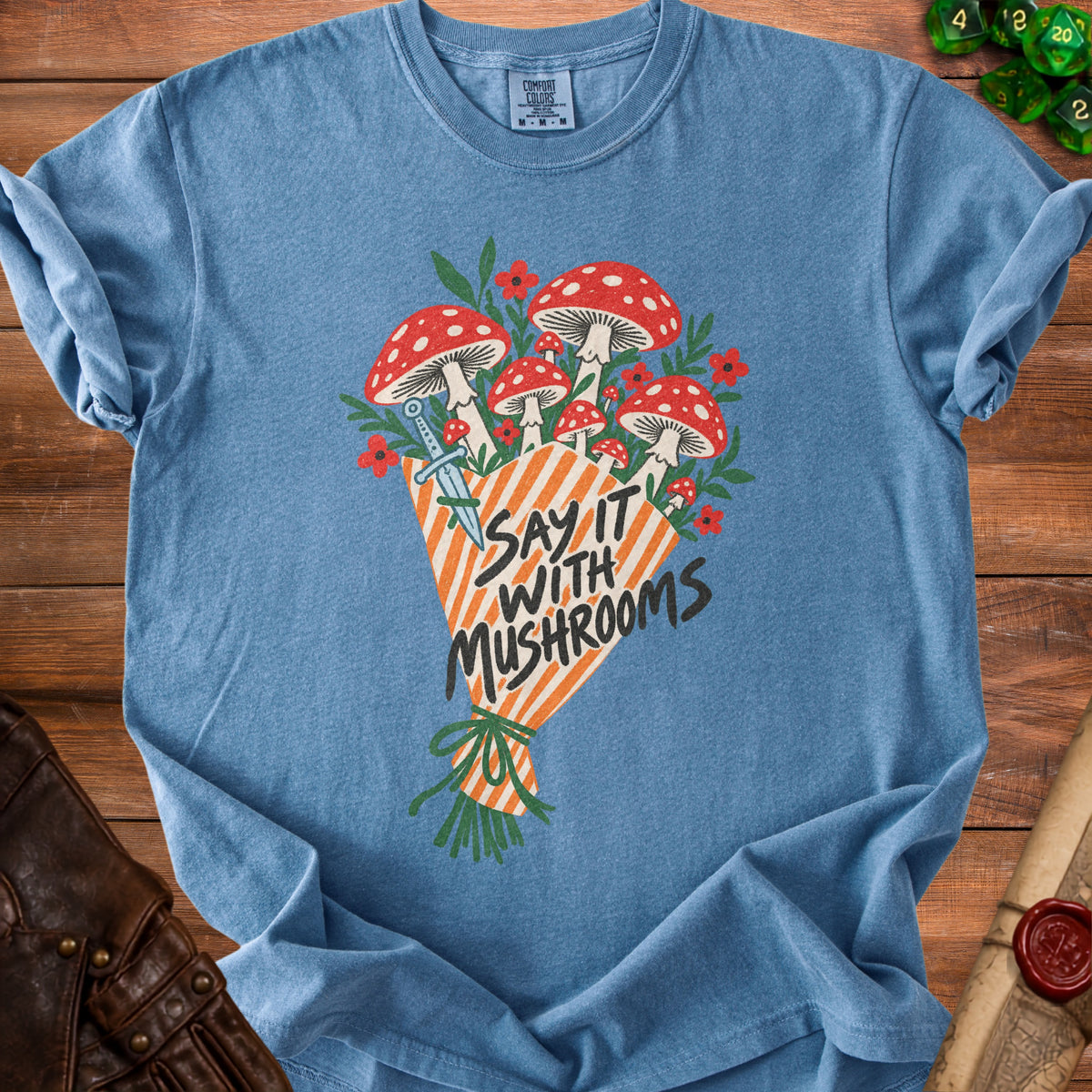 Blue t-shirt with a bouquet of mushrooms, a dagger, and text "Say It With Mushrooms".